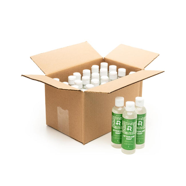 Open Box of 24 Bottles of Recovery Aftercare Soap with three bottles in front