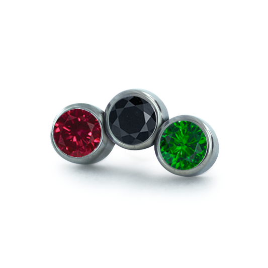 A 3-piece curved cluster featuring 1.5mm Ruby, Black, and Emerald Faceted Gems in threadless titanium bezel settings