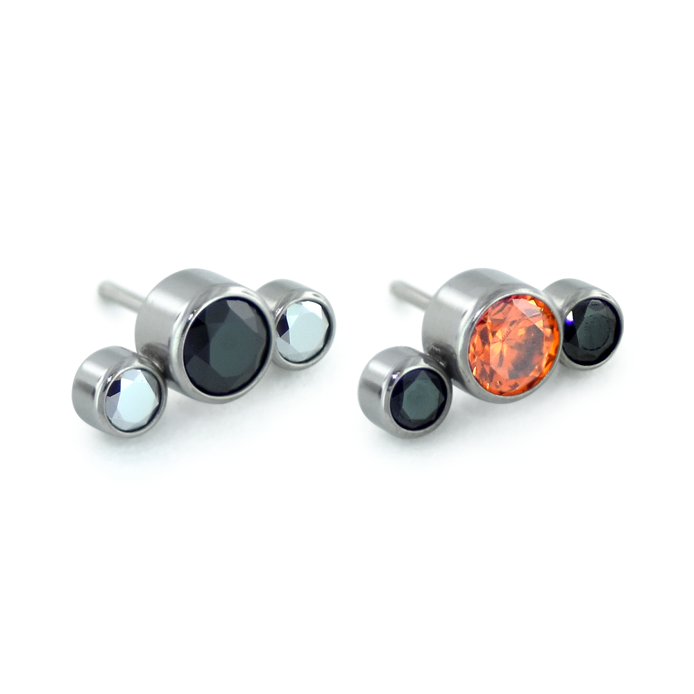 Two 3-piece threadless titanium gem cluster ends, one featuring light chrome and black gems while the other features orange and black gems.