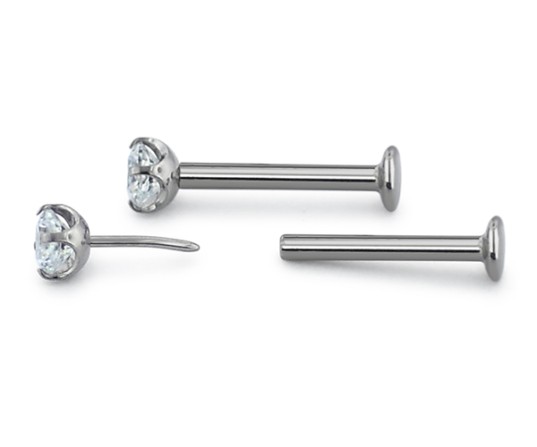 Two threadless titanium labret posts and gem ends with cubic zirconia gems. One gem end in the labret, the other separated from the labret.